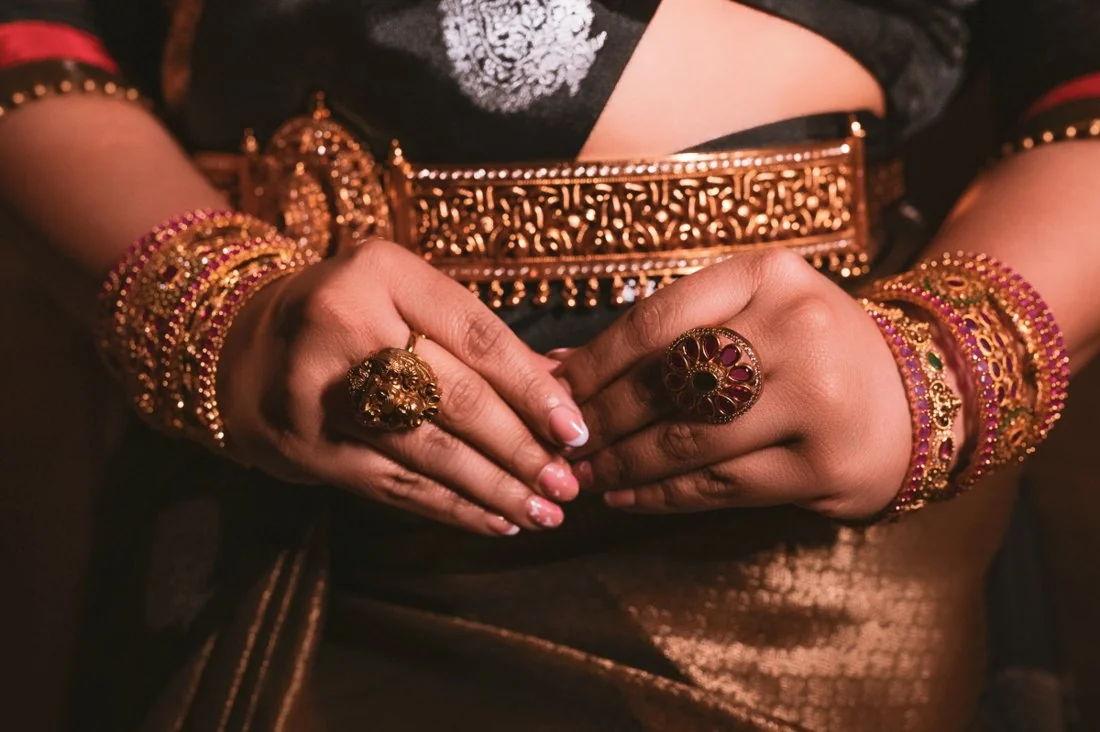 A woman’s folded hands with ornate bangles and jewellery
